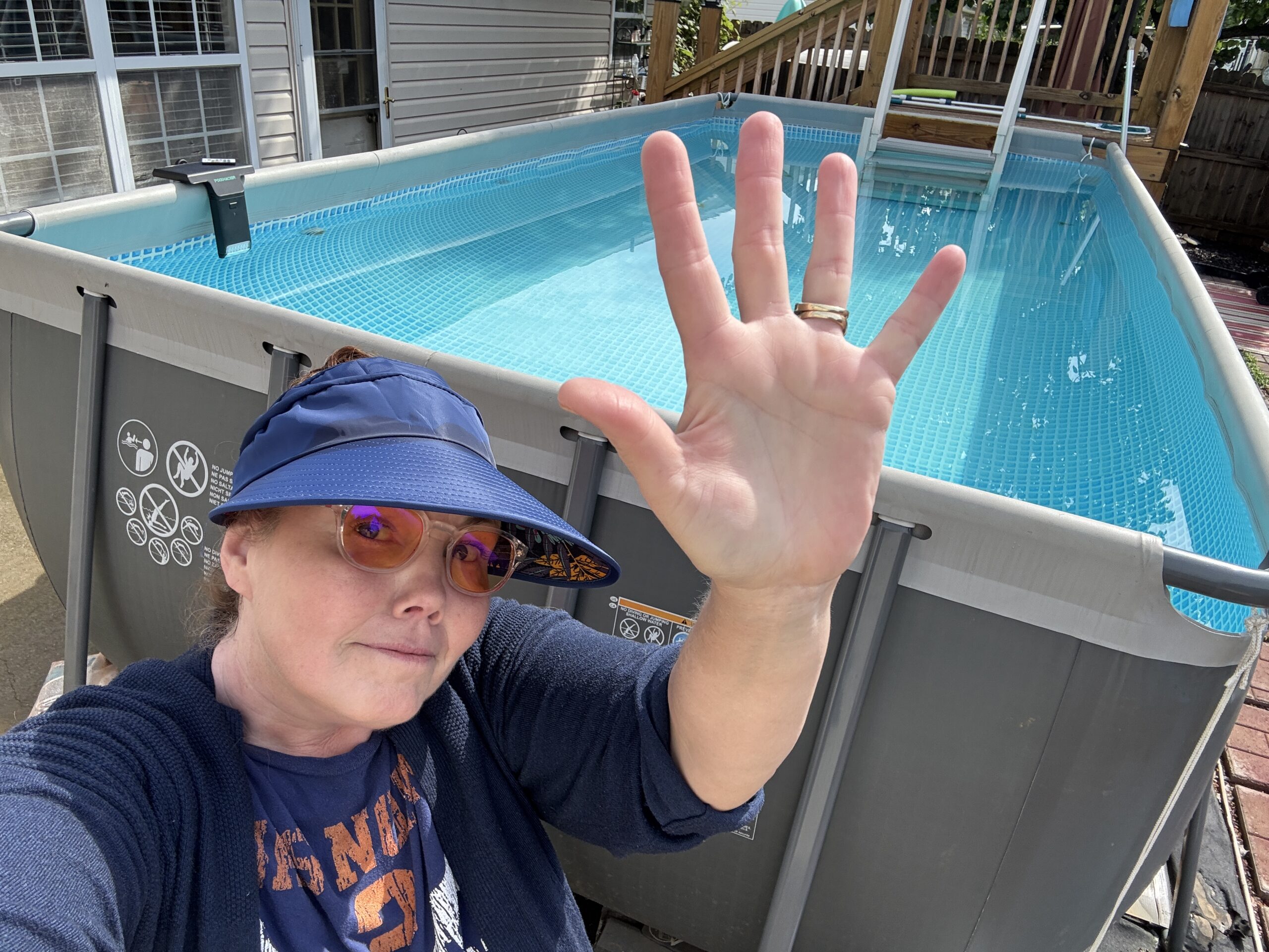 Brandi holding up five fingers in front of the Intex 18x9 Ultra XTR above-ground pool after 5 years of use